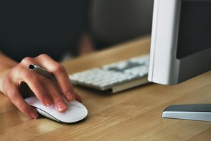 Eine Person am Computer und die Hand an der Maus