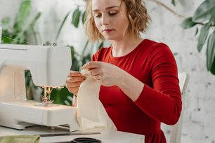 Frau näht Stoff an einer Nähmaschine