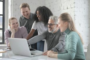 Personen sitzen zusammen vor einem Laptop